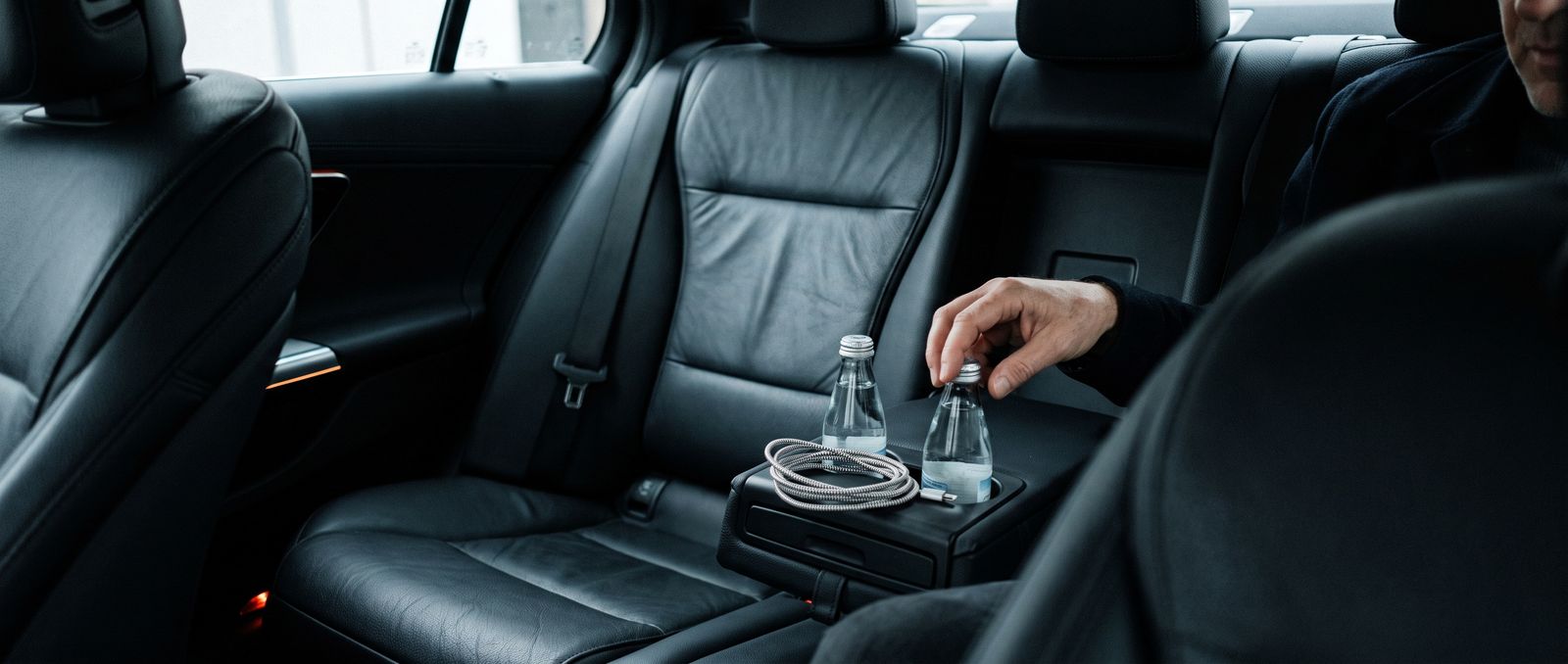 Intérieur cuir d'une berline premium, bouteilles d'eau et chargeur sur l'accoudoir